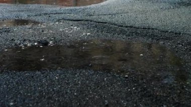 Kırık asfalta yağmur damlaları düşer. Yağmur arkaplanı