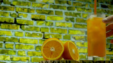 Barda kokteyl var. Bir adam soğuk bir kokteyli buzla karıştırıyor. Şeffaf bardakta sarı limonata. Portakal suyu