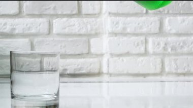 Yeşil limonatayı şeffaf bir bardağa, beyaz tuğla bir duvarın arka planına dök. Yeşil meyve suyu