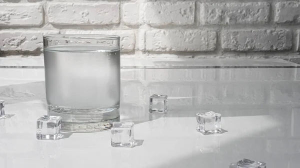Ivóvíz Átlátszó Pohárban Fehér Téglafal Hátterében Jégkockák Vízzel Egy Pohárban — Stock Fotó