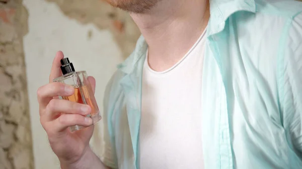 A man uses perfume, a man with a masculine perfume in his hands