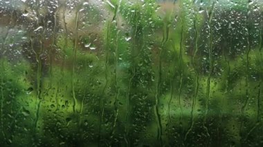 Pencerenin dışında yaz yağmuru, camda yağmur damlaları, arka planda yağmur