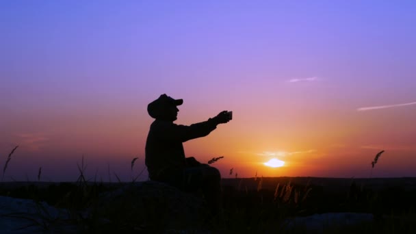 山の頂上にいた孤独な男が自撮りをし 10代の若者が日没時に自分の写真を撮る — ストック動画