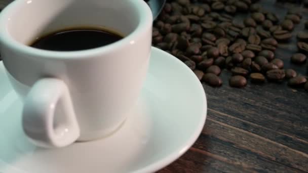 Geurige Koffie Een Koffiebeker Een Notenkleurige Houten Tafel Geroosterde Koffiebonen — Stockvideo
