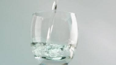 Beyaz arka planda bardakta su içmek. Şeffaf bir bardağa su dök.