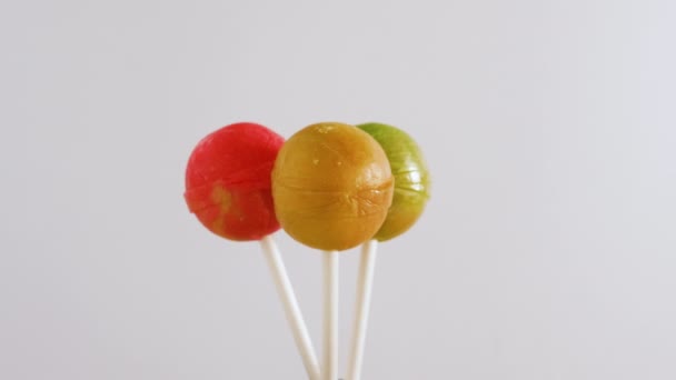 三个棒棒糖在白色背景上旋转 背景是糖果 — 图库视频影像