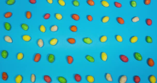 Time Lapse Animatie Van Gekleurde Snoepjes Een Blauwe Achtergrond Bovenaanzicht — Stockvideo