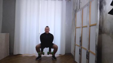 Dambıllarla erkek egzersizi. Ev antrenmanı. Ağır çekimde fiziksel egzersizler. Sağlıklı yaşam tarzı kavramı.