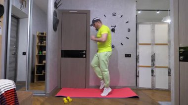 Antrenman sırasında koşarken. Evde bir paspasın üzerinde spor eğitimi. Antrenman sırasında bacak kaldırmak. Yavaş çekim.