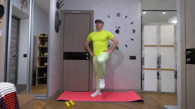 Antrenman sırasında yürüyoruz. Evde bir paspasın üzerinde spor eğitimi. Antrenman sırasında bacak kaldırma. Yavaş çekim.