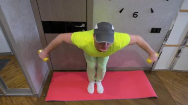 Elinde dambıllar, elinde dambıllar, elinde dambıllar, elinde dambıllarla antrenman yapıyor. Yavaş çekim.