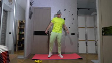 Spor salonunun paspası üzerinde antrenman. Genç adam evde egzersiz yaparken ayaklarını esnetir. Yavaş çekim