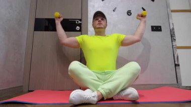 Kol kaslarını dambıllarla şişirmek. Spor salonunun paspası üzerinde antrenman. Yavaş çekim