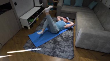 Spor paspası üzerinde bisiklet egzersizi yapmak, antrenman sırasında karın bölgesini pompalamak. Evde idman yapıyorum. Yavaş çekim.