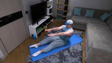 Karın egzersizi, dairede spor paspası üzerinde karın mekiği çeken bir adam. Yavaş çekim