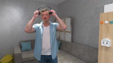 Genç adam kulaklık takıyor, adam evde kulaklıkla müzik dinliyor. Yavaş çekim