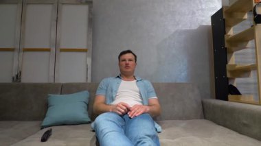 Gülümseyen Mutlu ve neşeli adam televizyon izlerken uzaktan kumandalı TV kanallarını değiştiriyor. Yavaş çekim