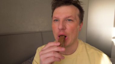 Genç adam yavaş çekimde çikolata yiyor. Adam fındıklı çikolata yiyor.