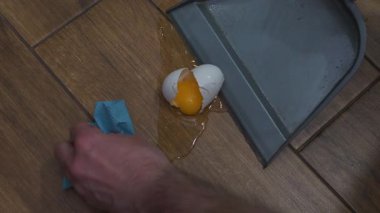 Yerde kırılmış tavuk yumurtası, yerdeki kiremitleri temizleyen adam. Yavaş çekim.