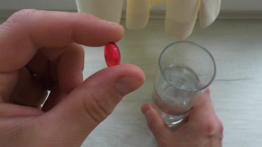 Bir insanın elindeki tablet kapsülü yakın plan tıbbi kapsül kırmızı tıbbi kapsül. Sağlık kavramı. Yavaş çekim