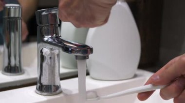 Musluk suyunun altında diş fırçası yıkamak, diş fırçasıyla diş fırçalamak. Yavaş çekim.