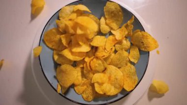 Patates cipsi yavaş çekimde tabağa düşer. Kızarmış patates fast food..