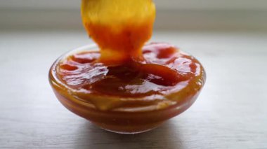 Patates cipsini ketçapa batır. Kasede kırmızı sos. Ağır çekim. Fast food soslu kızarmış patates.