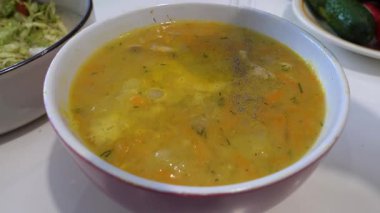 Karabiber çorbasıyla yemek serpin. Tabakta iştah açıcı sarı çorba, ağır çekim.