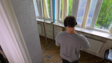  Bir faraş içine toprak süpürüyor. Yukarıdan bakıldığında, bir adam evdeki fayanslı zeminden toprağı süpürür. Yavaş çekim.