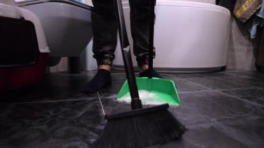 Süpürgeyle döşeme kiremitlerinden beyaz toz süpür. Süpürgeyle faraş pisliğini temizle. Yavaş çekim.