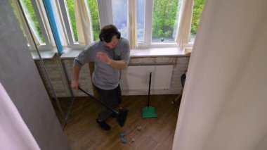 Müzik kulaklıklı dansçı, adam süpürgeyle toprağı faraş gibi süpürüyor. Süpürgeli temizlik. Daireleri müzikle ve dansla temizliyorum. Yaşam tarzı. Yavaş çekim