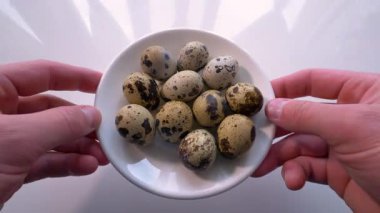 Bir adam mutfak masasına bıldırcın yumurtası koyar. Kabuklu yumurtadan çıkan yiyecekler..