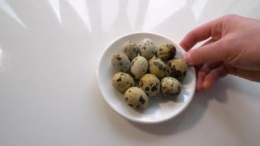 Bir adam mutfak masasına bıldırcın yumurtası koyar. Kabuklu yumurtadan çıkan yiyecekler.