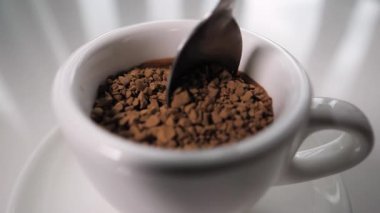 Hazır kahveyi kaşıkla fincanda karıştır. Granüllerde hazır kahve, ağır çekimde. Kahve fincanda sade içecek. Yakın plan..