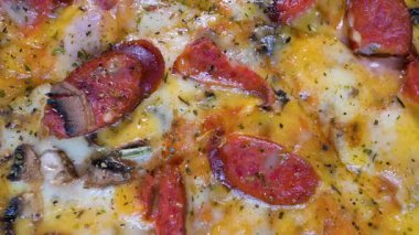 Sosisli ve mozzarella peynirli iştah açıcı pizza, işlenmiş peynir, siyah bir arka planda, hareket halinde dönen bir pikap üzerinde. Üst Manzara. Yakın plan.