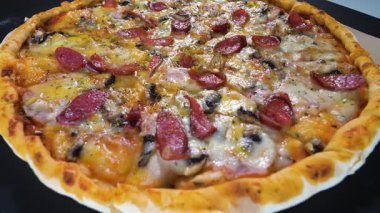 Sosisli ve mozzarella peynirli iştah açıcı pizza, erimiş peynir, siyah arka planda döner döner döner döner döner döner. Yakın plan.