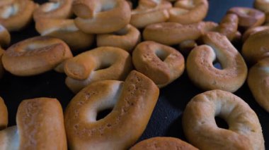 Kızarmış Rusks halkaları, siyah masada simit pişirme, döner döner tablada dönme. Yakın plan.