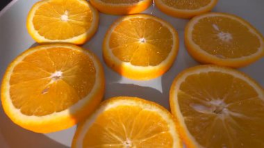 Bir tabakta halka halinde dilimlenmiş portakal meyvesi, döner döner döner döner döner tablada. Ağır çekim. Yakın plan.