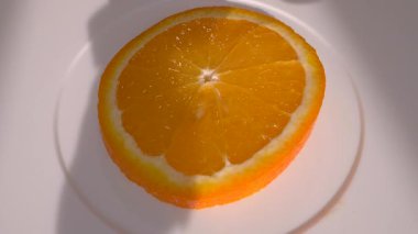 Dilimlenmiş portakallı meyve halkaları, beyaz bir pikapta hareket halinde dönüyor. Ağır çekim. Yakın plan..