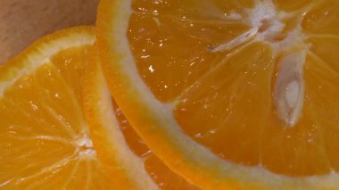 Tahta kesme tahtasında dönen portakal dilimleri. Meyve portakalı halka şeklinde kesilmiş. Ağır çekim. Yakın plan.