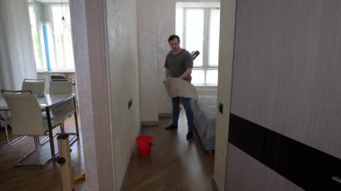 Bir dairede bir adam ahşap bir paspasla yerleri yıkıyor. Ev temizliği, kaplamaları bez parçasıyla yıkamak, ağır çekim..