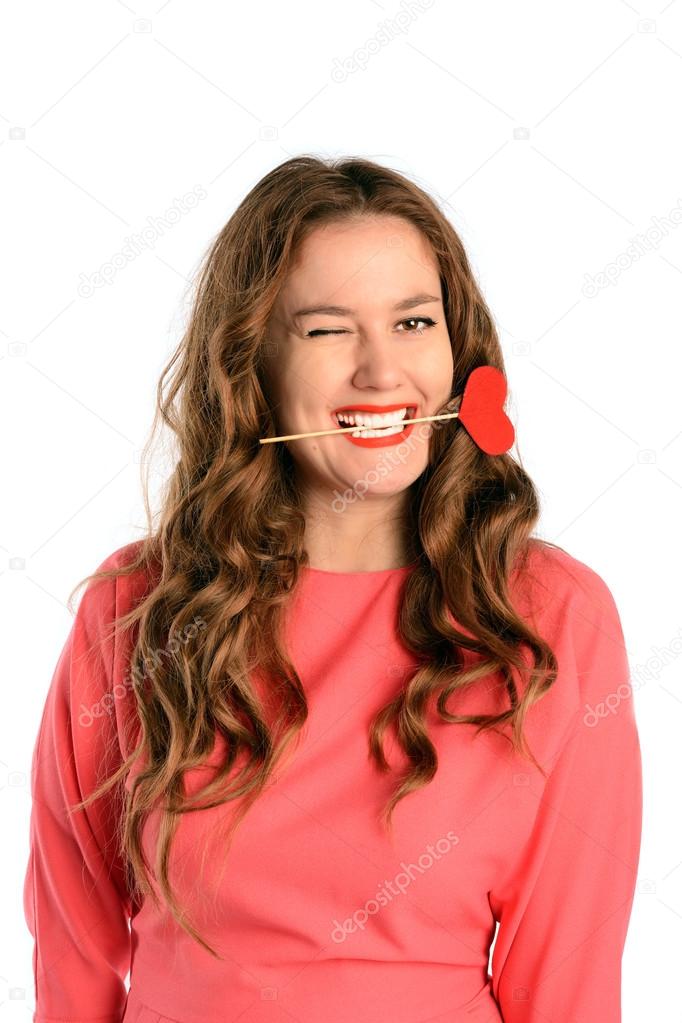 Brunette long hair young woman biting heart on a stick. Valentines day love and relationships concept.