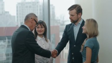 Kendinden emin ve çekici iş takım tanışın ve meşgul modern ofis binası lobide el sallamak