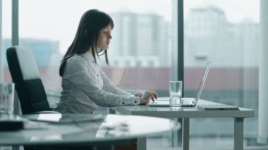 modern ofis bir dizüstü bilgisayarda çalışan genç iş kadını. durmadan geri acıyor çünkü