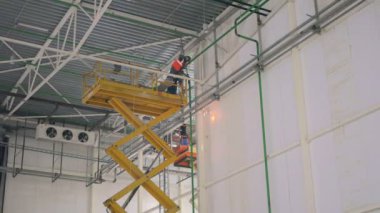 büyük ve modern sanayi depoda bir yükseklikte turuncu Asansör Kaynakçı çalışır