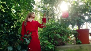 güzel genç kadın gülümsüyor ve Botanik bahçe içinde etrafına bakıyor