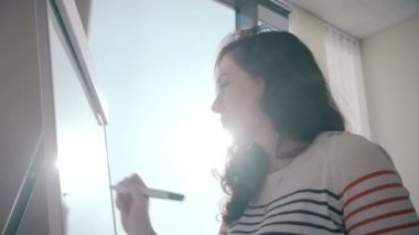 Güzel genç öğrenci kız yazma bilgi plastik, yazmak yönetim kurulu ve gülümsüyor