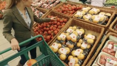 Kadın modern süpermarkette frash domates seçilmesi