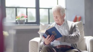 yaşlı beyaz adam bir kitap okuma ve modern bir dairede lezzetli bir çay içme