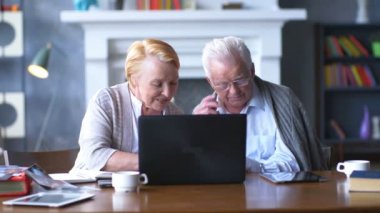 Üst düzey çift websurfing dizüstü bilgisayar ile Internet üzerinde. Mutlu yaşlı adam ve bilgisayar kullanan kadın